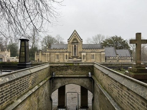 A brick passage leading toward a stone cemetery chapel