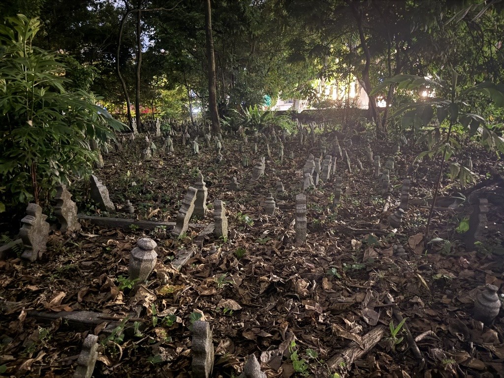 Small stone memorials beneath trees on a wooded hillside